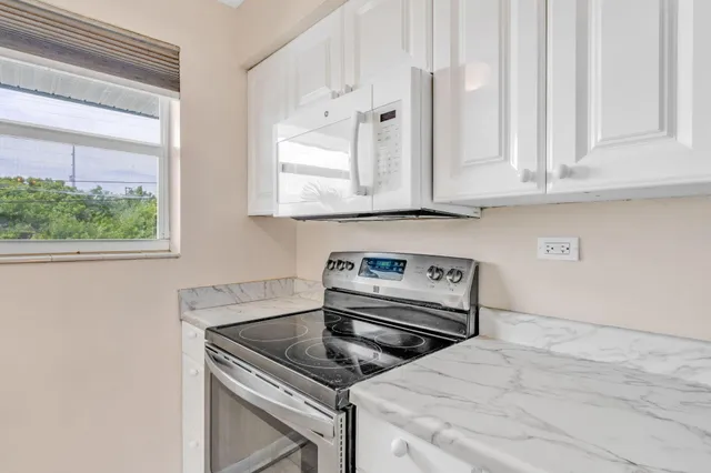 a kitchen with white cabinets and a stove with a sink