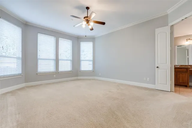 an empty room with chandelier fan and windows