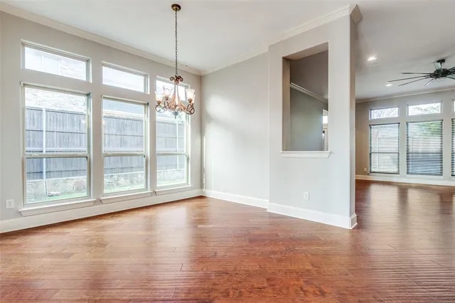 a view of an empty room with window and hardwood floor