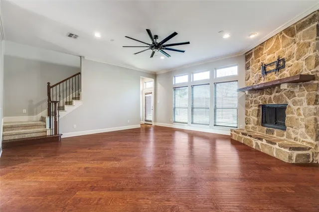 a view of a livingroom with wooden floor a ceiling fan and windows