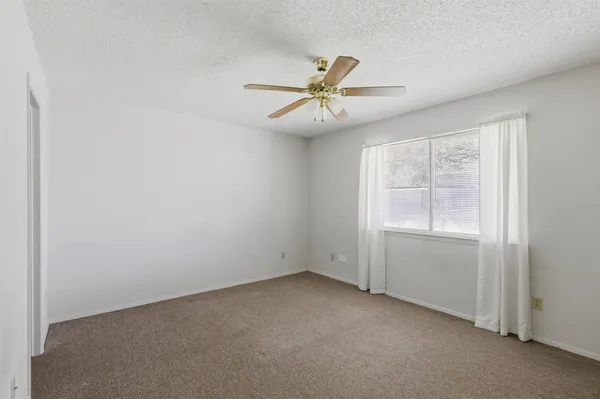an empty room with a window and a fan