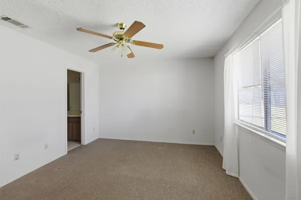 an empty room with a window and a ceiling fan