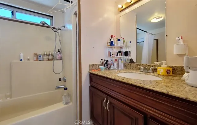 a bathroom with a granite countertop sink a mirror and a bathtub