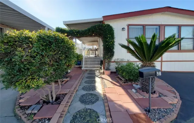 a vase of flowers sitting on a floor in front of a house