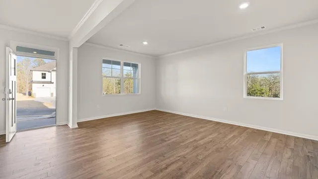 an empty room with wooden floor and windows