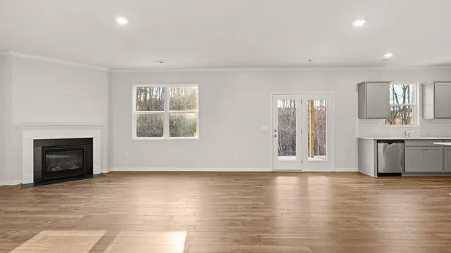 a view of an empty room with window and wooden floor