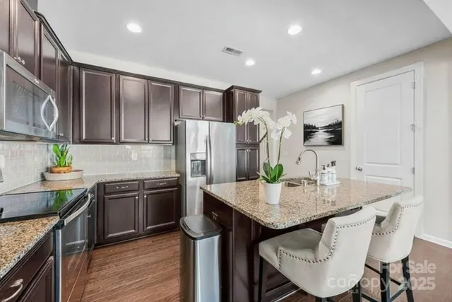 a kitchen with kitchen island granite countertop stainless steel appliances cabinets a sink and a refrigerator