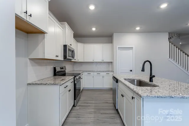 a kitchen with stainless steel appliances granite countertop a stove a sink and a microwave