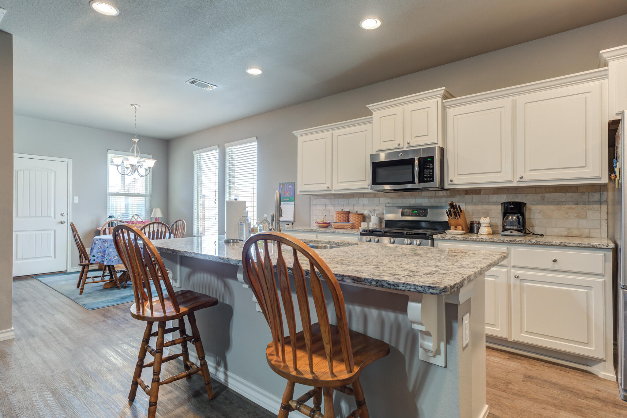 5219 Kemper Street Lubbock, TX 79416 - Photo 14 of 38 a kitchen with stainless steel appliances granite countertop a stove a sink a microwave a dining table and chairs
