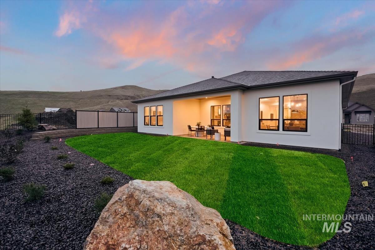 7615 Brown Way Eagle, ID 83714 - Photo 41 of 43 Contemporary exterior featuring a covered patio, expansive back lawn, and surrounding landscape with decorative rock