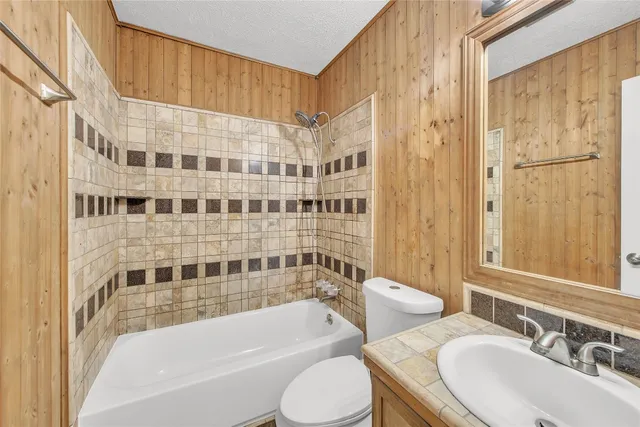 a bathroom with a bathtub shower sink vanity and toilet
