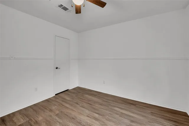 an empty room with wooden floor cabinet and ceiling fan