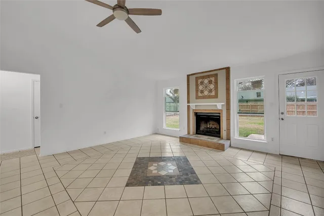 a view of a livingroom with a fireplace a ceiling fan and window