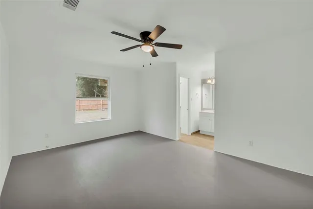 an empty room with windows and fan