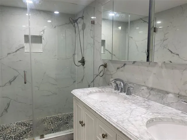 a bathroom with a granite countertop sink a shower and a mirror