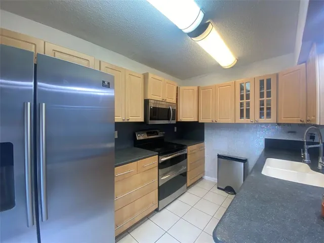 a kitchen with stainless steel appliances granite countertop a refrigerator and a stove top oven