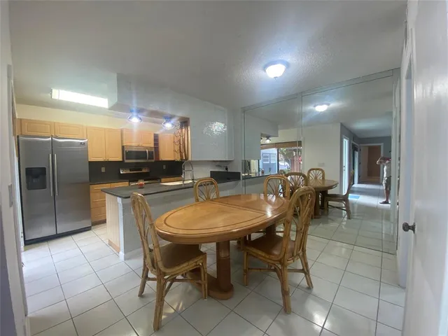 a dining area with a table chairs and a refrigerator