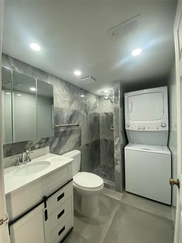 a bathroom with a granite countertop sink a toilet a mirror and shower