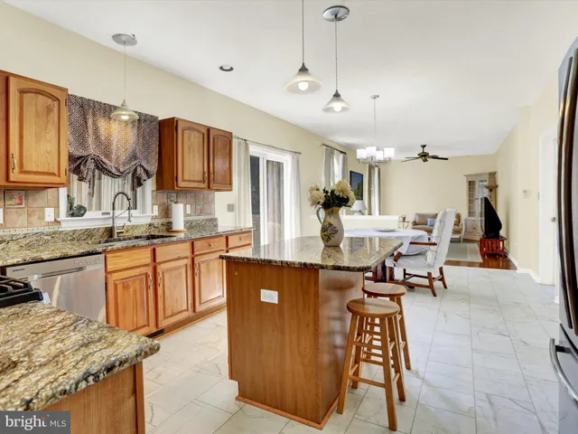 a kitchen with stainless steel appliances granite countertop wooden cabinets a stove a sink and a microwave