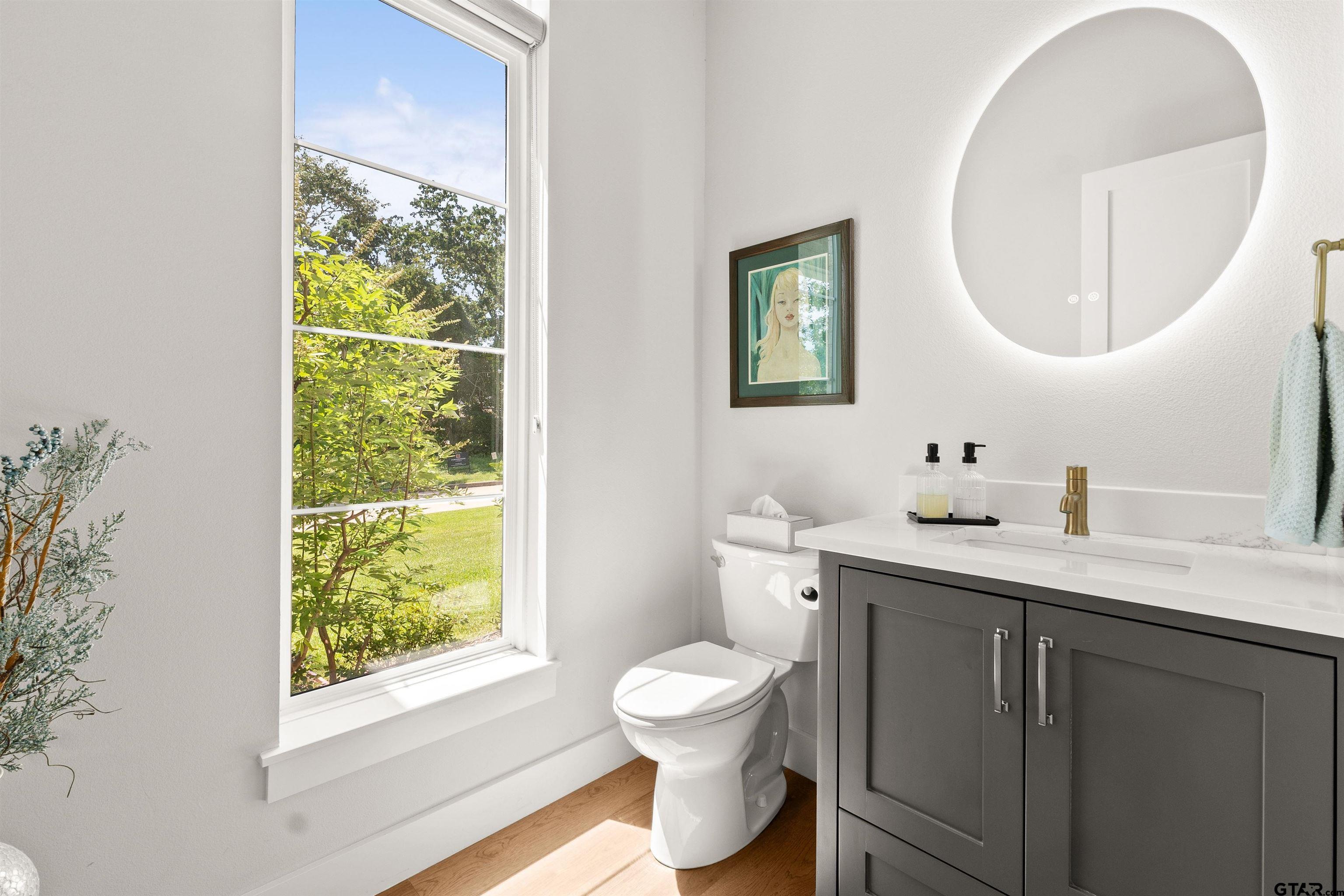 a bathroom with a toilet a sink a mirror and a window