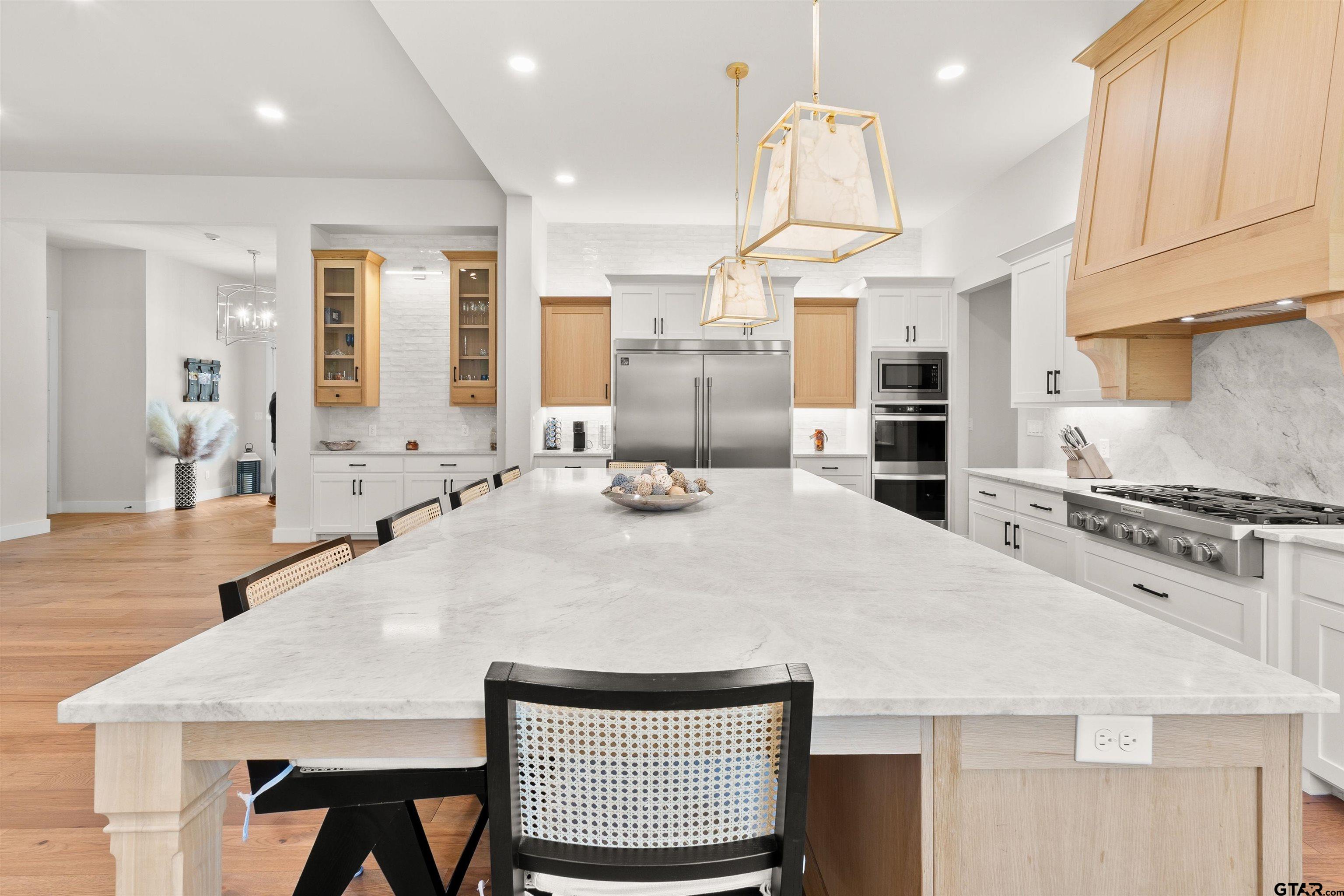 2895 Stewart Way Tyler, TX 75709 - Photo 41 of 44 a large kitchen with kitchen island a stove a sink a refrigerator and white cabinets with wooden floor