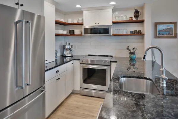 a kitchen with stainless steel appliances granite countertop a stove a sink and a refrigerator