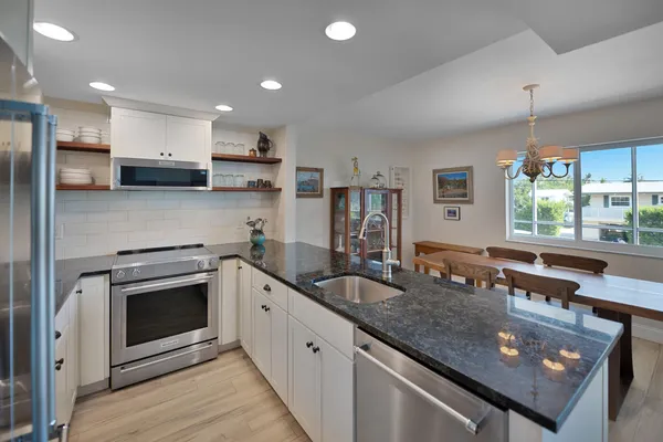 a kitchen with stainless steel appliances granite countertop a sink a stove and a refrigerator