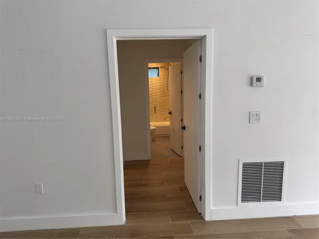 a view of a hallway with wooden floor and a living room