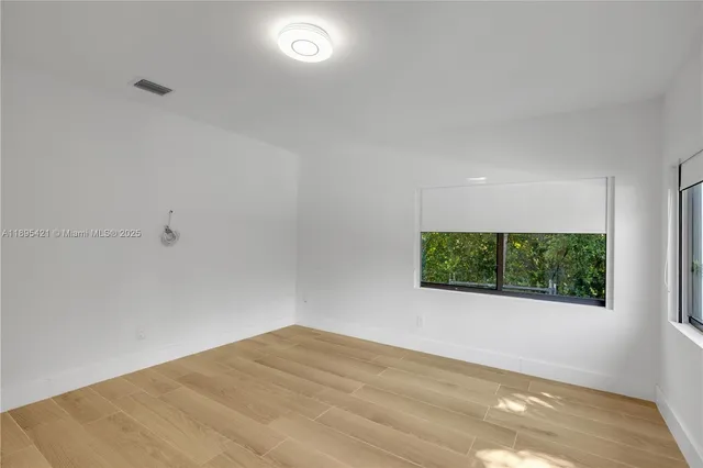a view of a big room with wooden floor and windows