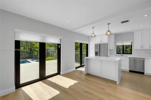 a large white room with kitchen view and large windows