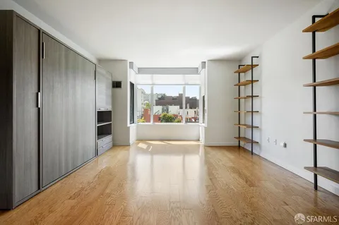 a view of an empty room with a window and wooden floor