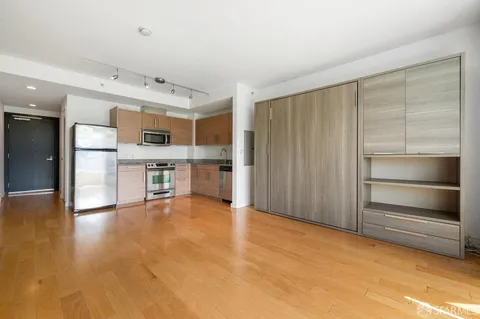 a view of kitchen with stainless steel appliances wooden floor and window