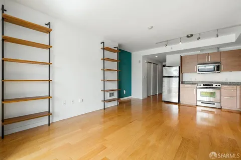 a view of an empty room with a window and kitchen