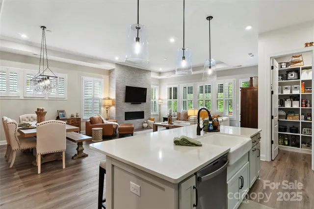 a kitchen with stainless steel appliances granite countertop a stove a sink dishwasher a dining table and chairs with wooden floor