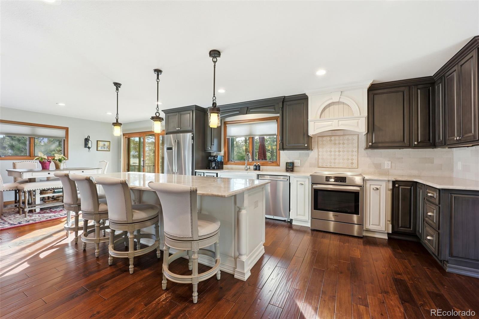 5000 South Perry Park Road Sedalia, CO 80135 - Photo 11 of 50 a kitchen with stainless steel appliances granite countertop a stove top oven a sink a dining table and chairs with wooden floor
