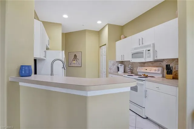 a kitchen with stainless steel appliances a sink a stove a refrigerator with white cabinets