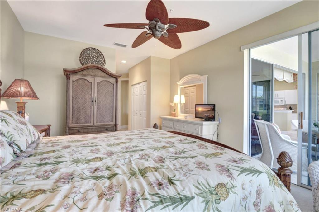 784 Carrick Bend Circle, Unit 101 Naples, FL 34110 - Photo 21 of 34 a bedroom with a bed a chandelier and dresser