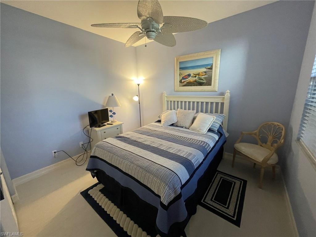 784 Carrick Bend Circle, Unit 101 Naples, FL 34110 - Photo 29 of 34 a bedroom with a bed and a chandelier