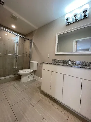 a bathroom with a granite countertop sink and a toilet