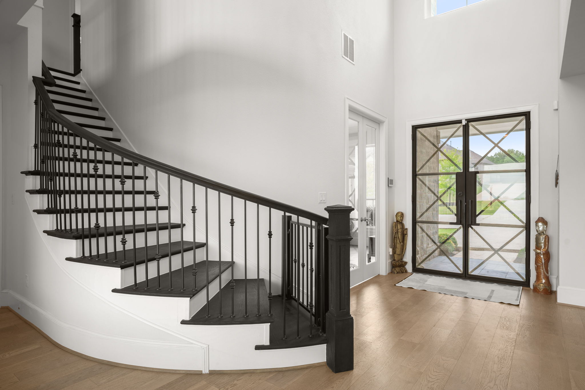 104 Lodestone Cove Austin, TX 78738 - Photo 24 of 40 A grand, curved staircase with elegant iron balusters welcomes you into a luminous entry with rich wood flooring.