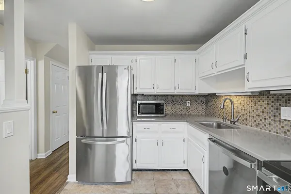 a kitchen with white cabinets white stainless steel appliances and refrigerator
