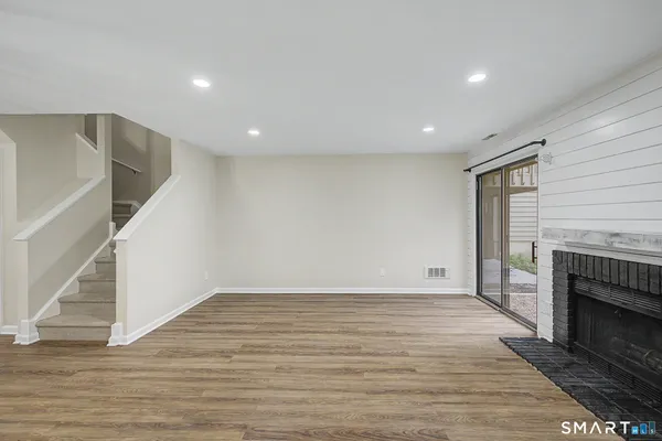 a view of empty room with wooden floor and fireplace
