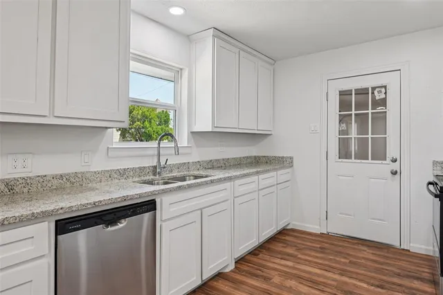 a kitchen with granite countertop a sink stainless steel appliances white cabinets and a window