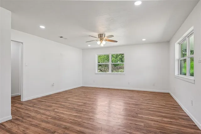 an empty room with windows and a ceiling fan