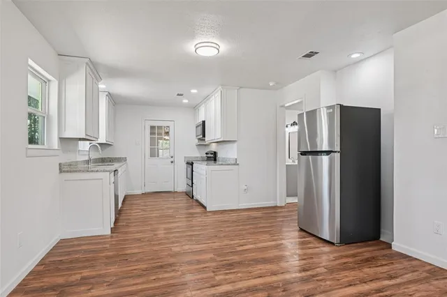 a kitchen with a refrigerator and white cabinets