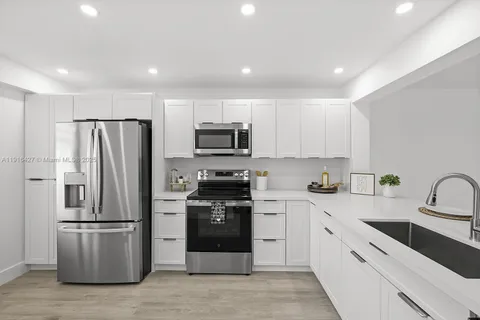 a kitchen with refrigerator a sink and white cabinets