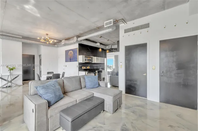 a living room with stainless steel appliances furniture a kitchen view and a chandelier