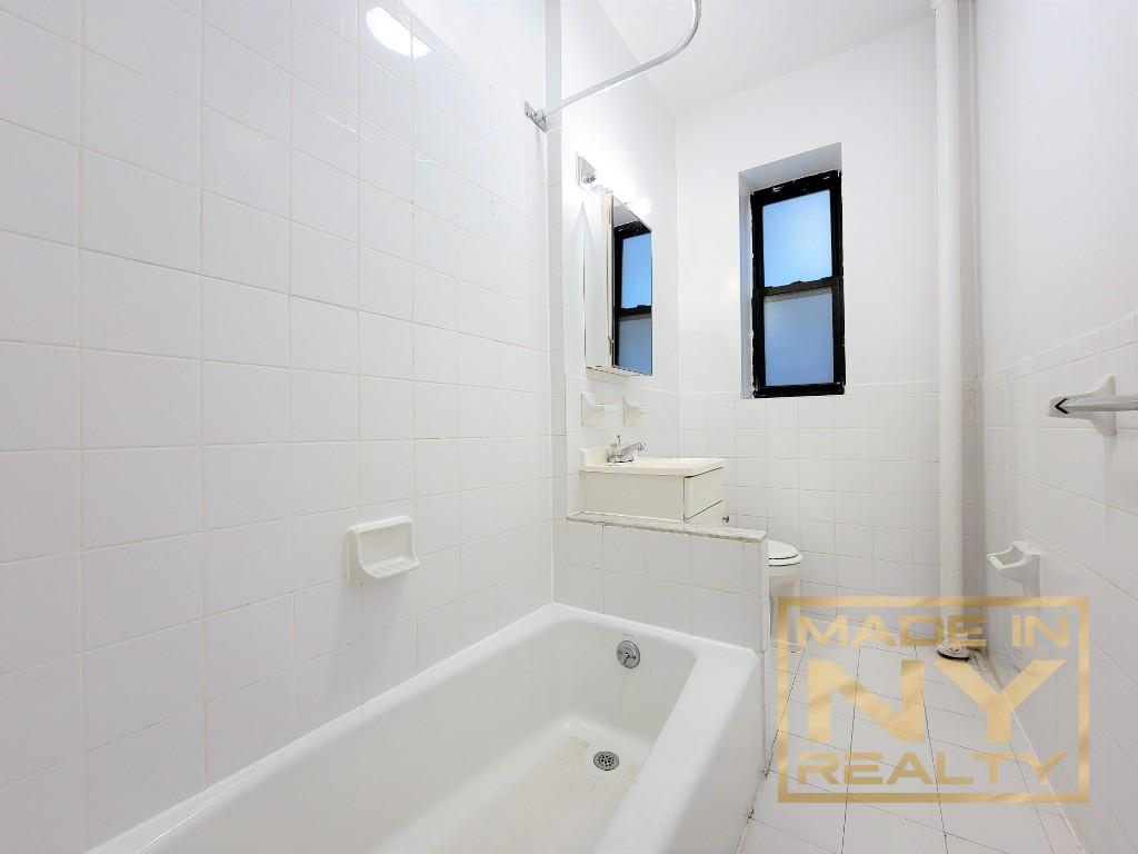 29-07 31st Avenue, Unit 1E Queens, NY 11106 - Photo 5 of 7 a bathroom with bathtub sink vanity and mirror