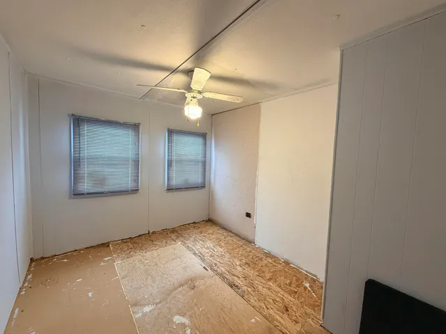 a view of an empty room with window and chandelier fan