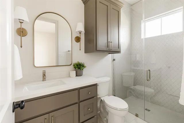 a bathroom with a granite countertop toilet sink and mirror